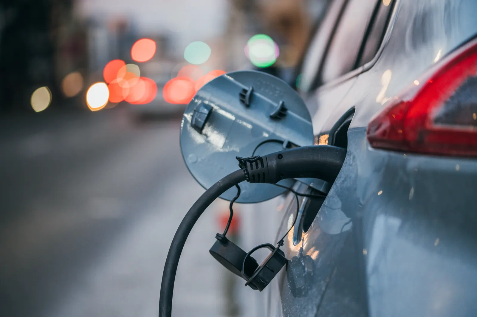 Primer plano de un coche eléctrico conectado a un poste de recarga.