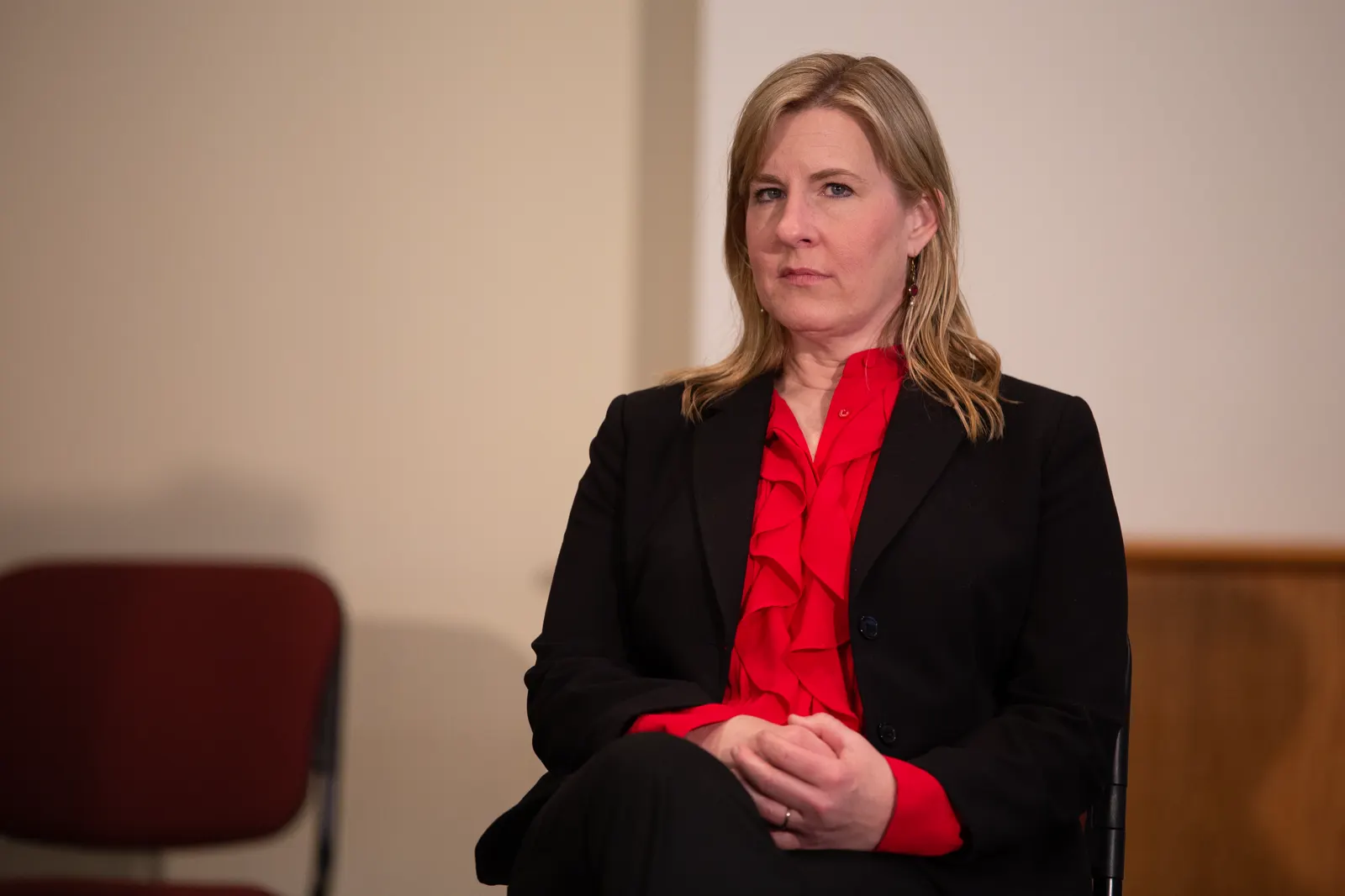 Melissa Hortman, con traje negro y blusa roja, sentada y mirando al frente durante un acto público en el Capitolio de Minnesota.