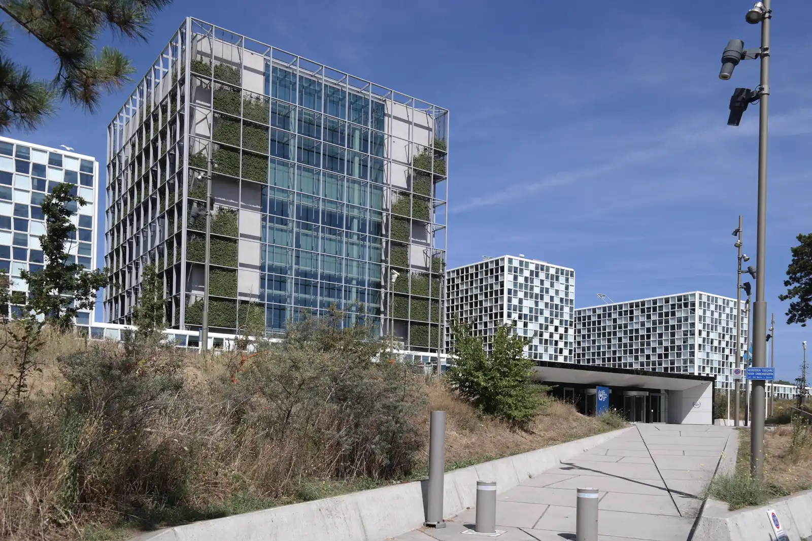 Edificios de la sede de la Corte Penal Internacional en La Haya: una torre acristalada con vegetación en las terrazas y, a la derecha, los bloques de fachada ajedrezada junto a la entrada principal.