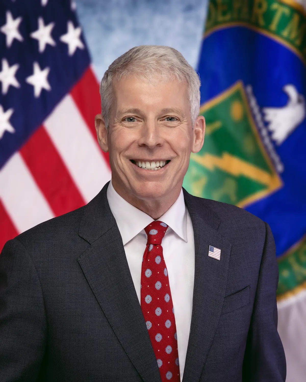 Retrato oficial de Chris Wright, secretario de Energía de Estados Unidos, con traje oscuro ante una bandera estadounidense.