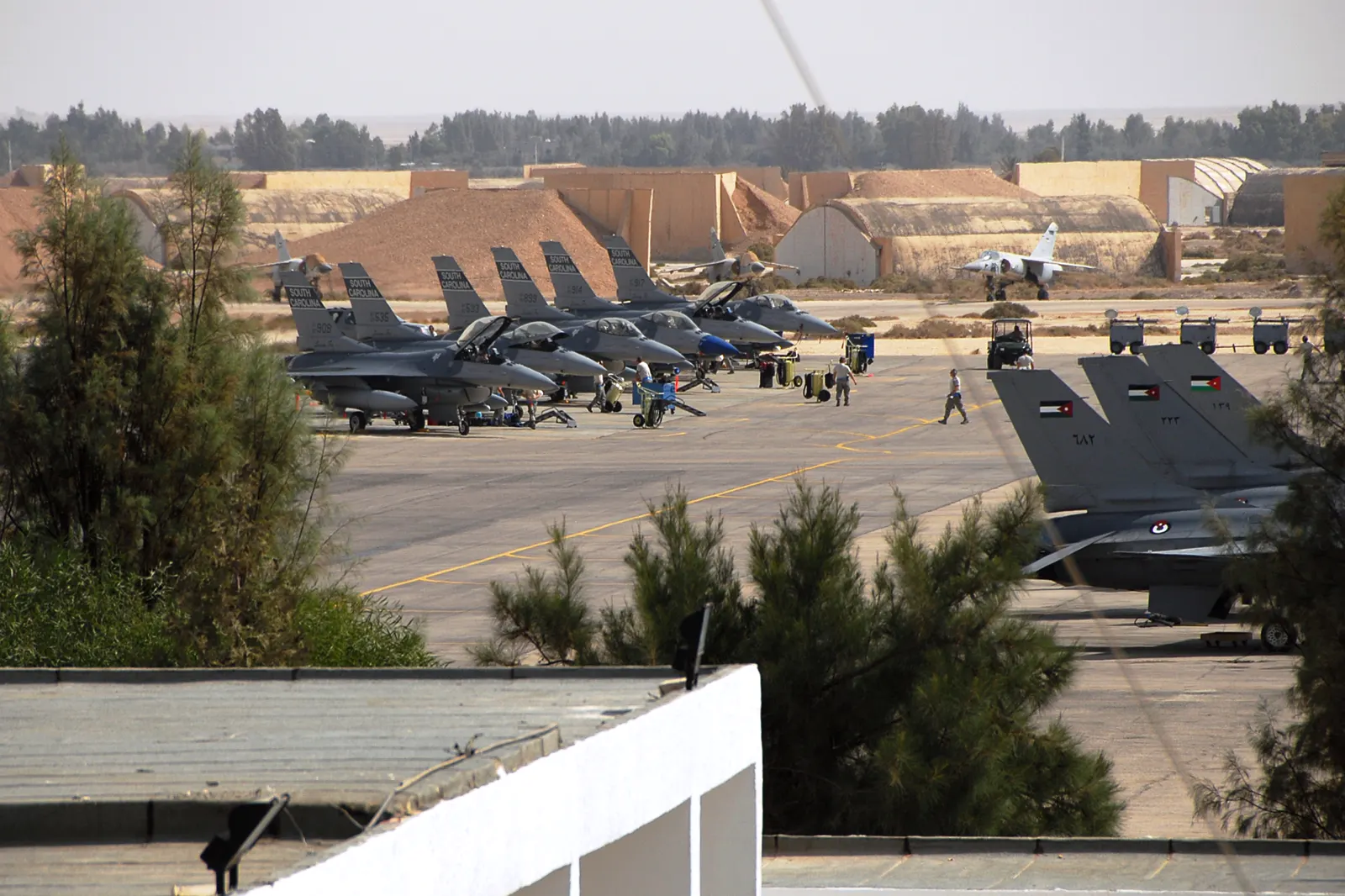 Cazas F-16 estadounidenses y jordanos aparcados en la plataforma de la base aérea de Muwaffaq Salti, en Al Azraq (Jordania), con refugios de hormigón para aviones al fondo.
