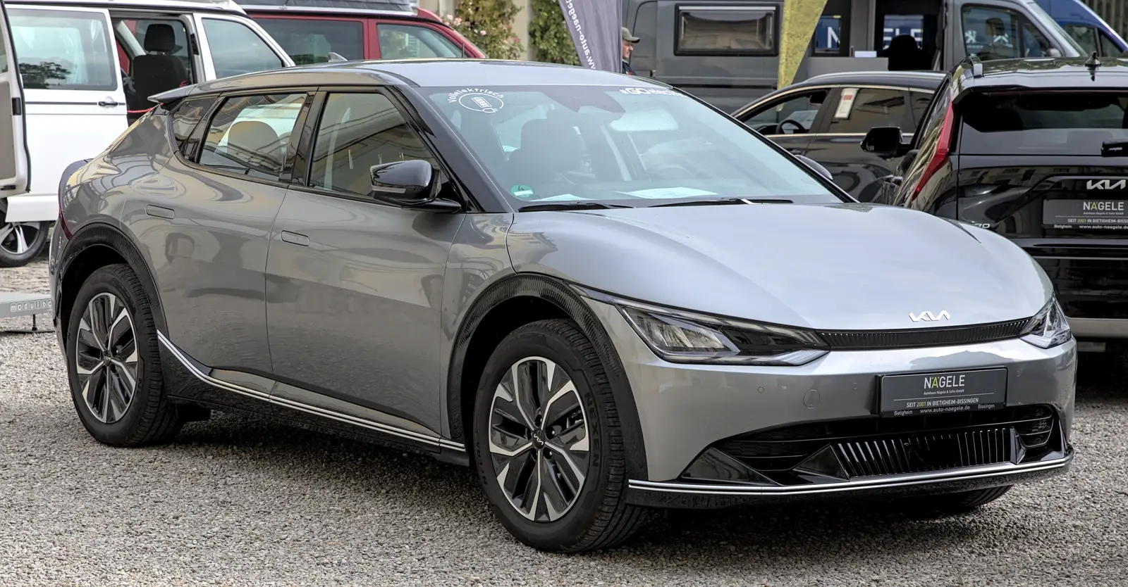 Un turismo eléctrico Kia EV6 de color gris, aparcado en una exposición de vehículos al aire libre