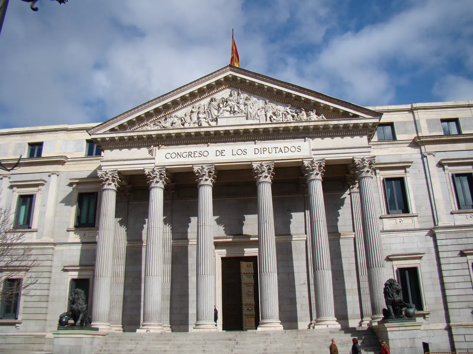 Fachada principal del Palacio de las Cortes, con su pórtico de columnas, el frontón esculpido y los dos leones de bronce que flanquean la escalinata.