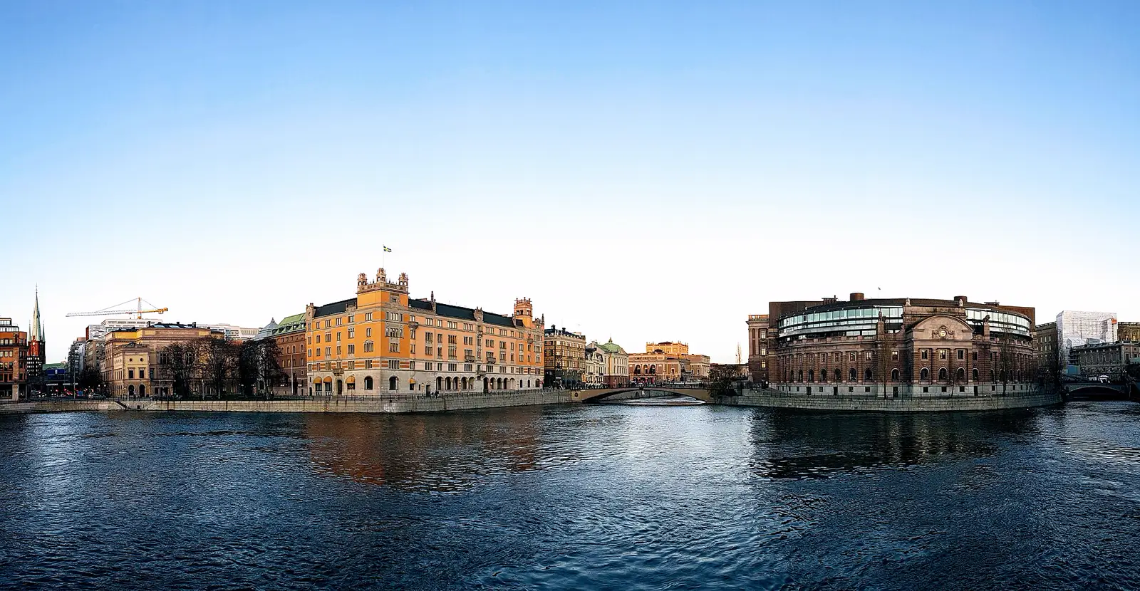 Vista desde el agua de Rosenbad, sede del Gobierno sueco, con la bandera de Suecia ondeando, y a la derecha el edificio del Riksdag, el Parlamento, en el centro de Estocolmo