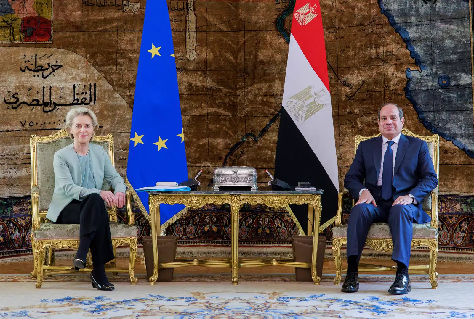Ursula von der Leyen y Abdelfatah al Sisi, sentados en butacas doradas separadas por una mesa baja, ante las banderas de la Unión Europea y de Egipto y un gran mapa antiguo de Egipto en árabe