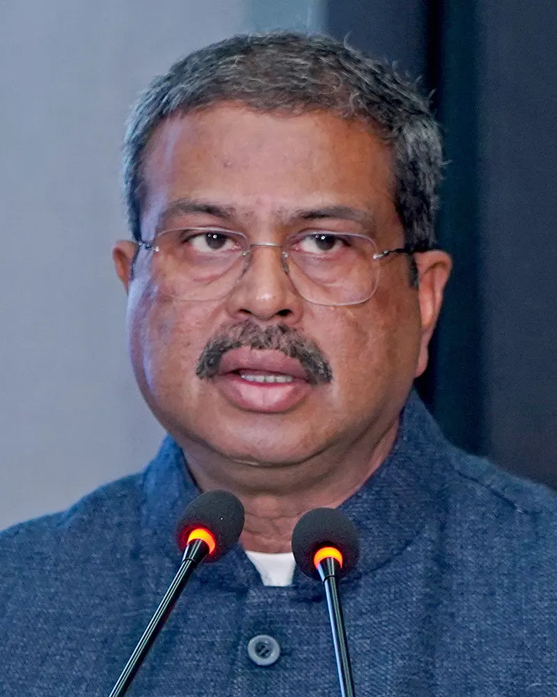 Dharmendra Pradhan, hombre de mediana edad con barba y bigote canosos y gafas, vestido con kurta blanca y chaleco oscuro, habla ante un micrófono en un acto oficial.