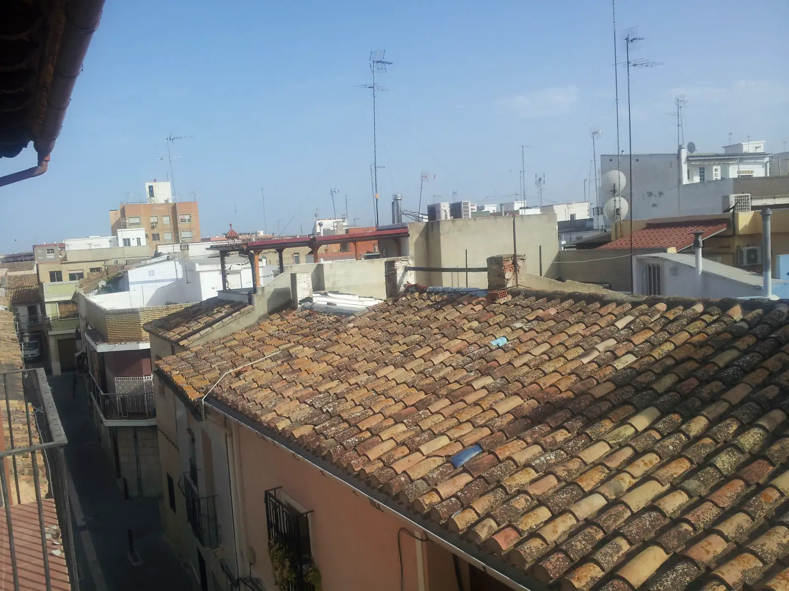 Tejados de teja árabe y edificios de viviendas del casco urbano de Manises bajo un cielo despejado, vistos desde una altura.