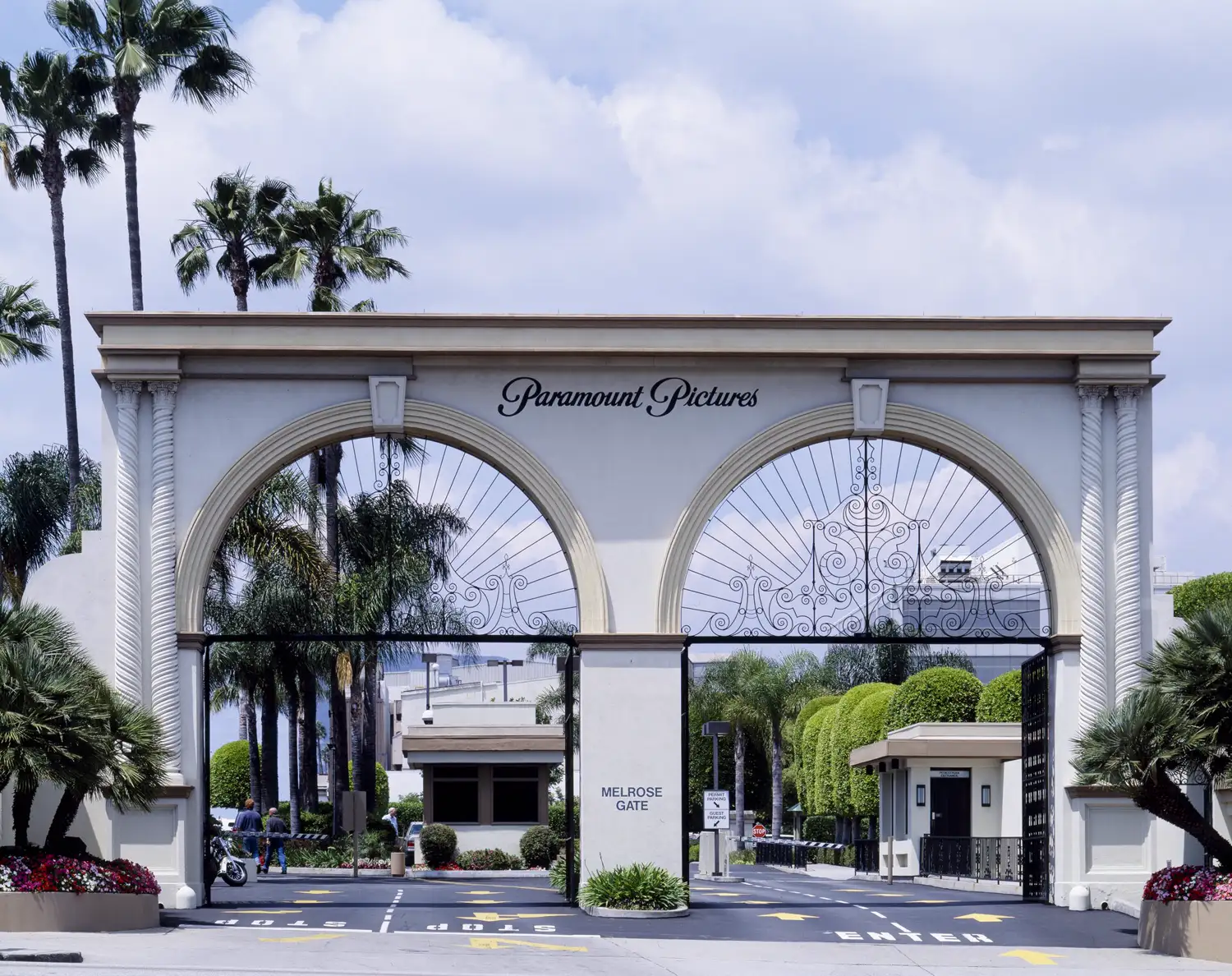 Arco de entrada de los estudios Paramount Pictures, con el rótulo Melrose Gate, palmeras al fondo y la calzada de acceso vacía