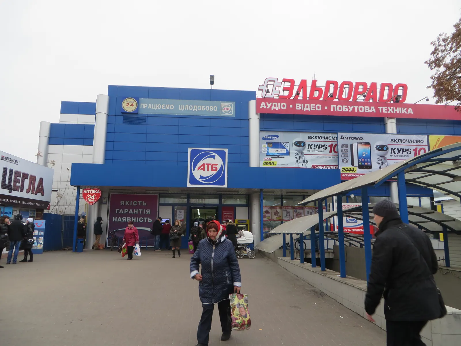 Fachada azul de un supermercado de la cadena ucraniana ATB en Chernígov, con su logotipo sobre la entrada y varias personas caminando delante.