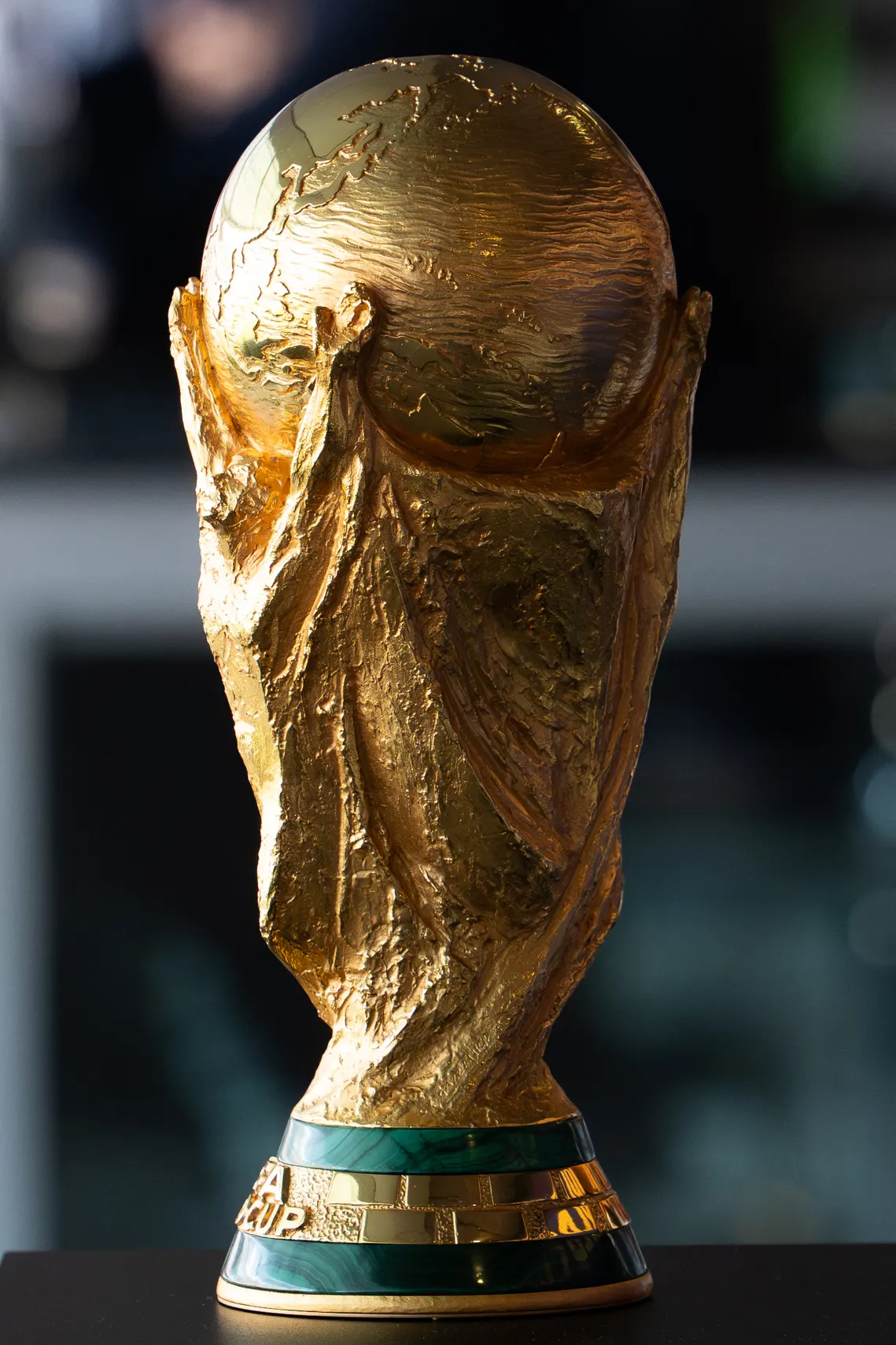 La Copa del Mundo de la FIFA en primer plano, dorada, con la base de malaquita verde