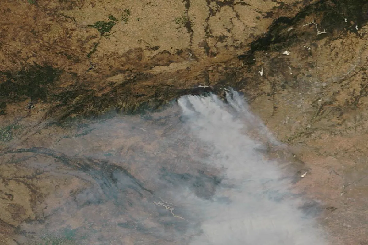 Imagen de satélite del centro de la Península el 26 de julio de 2026: sobre la línea oscura de la sierra, en el centro de la imagen, se levantan varias columnas de humo blanco que se funden en una gran mancha grisácea extendida hacia el sur y el sureste sobre la llanura parda de Castilla; en el margen derecho se distingue el gris del área metropolitana de Madrid.