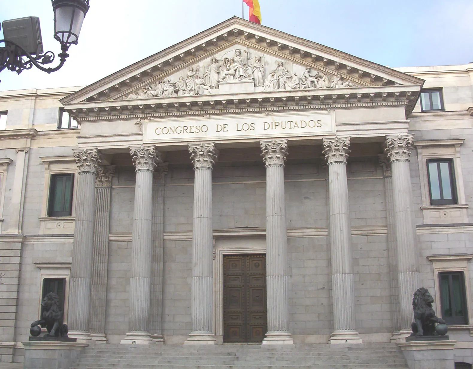 Fachada principal del Congreso de los Diputados en Madrid: seis columnas corintias bajo un frontón esculpido, con el rótulo «Congreso de los Diputados» y los dos leones de bronce a los lados de la escalinata.