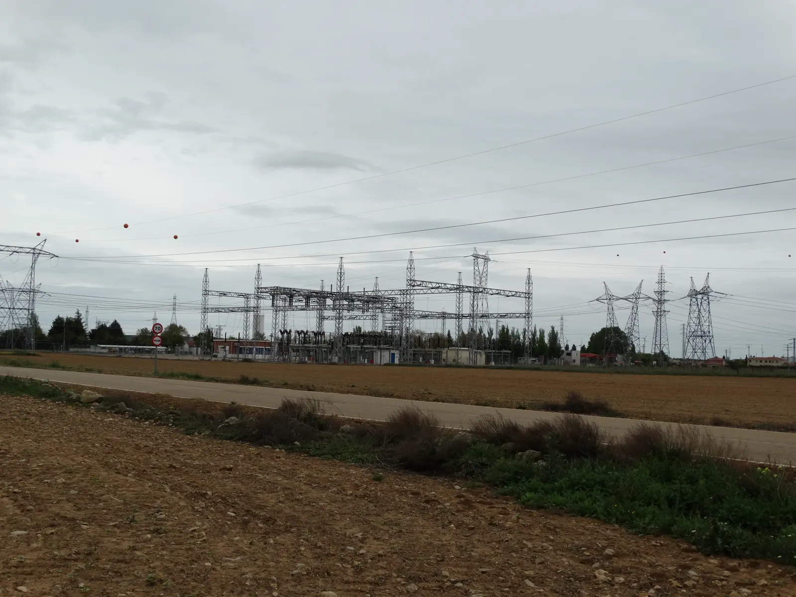 Subestación eléctrica de La Mudarra (Valladolid) con torres de alta tensión y cables sobre campos de labor en un día nublado