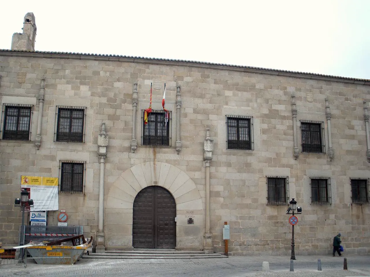 Fachada de granito del Palacio de Blasco Núñez Vela, en Ávila, con una placa que reza «Palacio de Justicia» junto a la portada de arco de medio punto, ventanas enrejadas en dos alturas y las banderas de España y de Castilla y León sobre el balcón central.