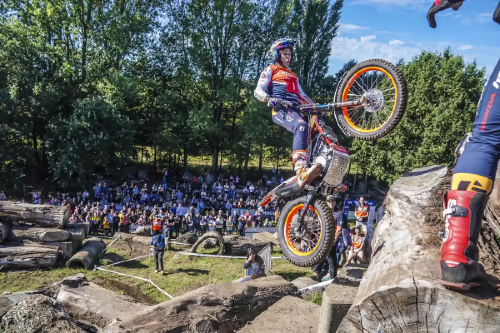 Toni Bou salta con su moto de trial entre bloques de piedra y troncos ante una grada llena de público en el circuito de Zelhem.