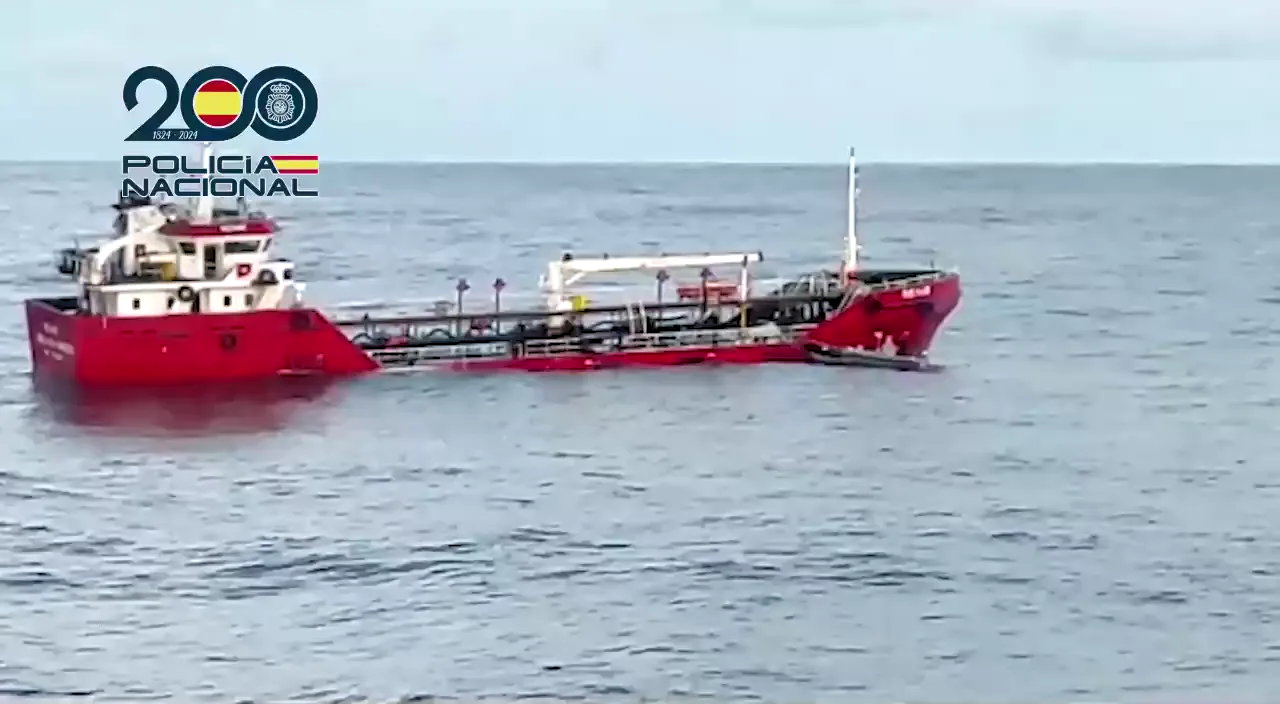 Un buque cisterna de casco rojo y superestructura blanca, sin nadie visible a bordo, permanece parado en mar abierto bajo un cielo gris; en la esquina superior izquierda, el logotipo del bicentenario de la Policía Nacional.